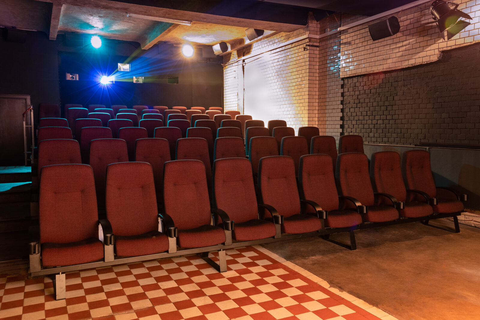 Kinosaal des Filmrauschpalasts mit roten Sesseln, Backsteinwand und Schachbrettboden