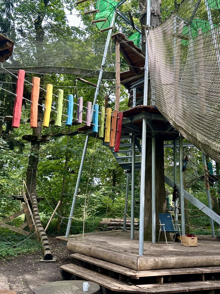 Bunte Kletterelemente und Netze zwischen Bäumen im AbenteuerPark Kressbronn