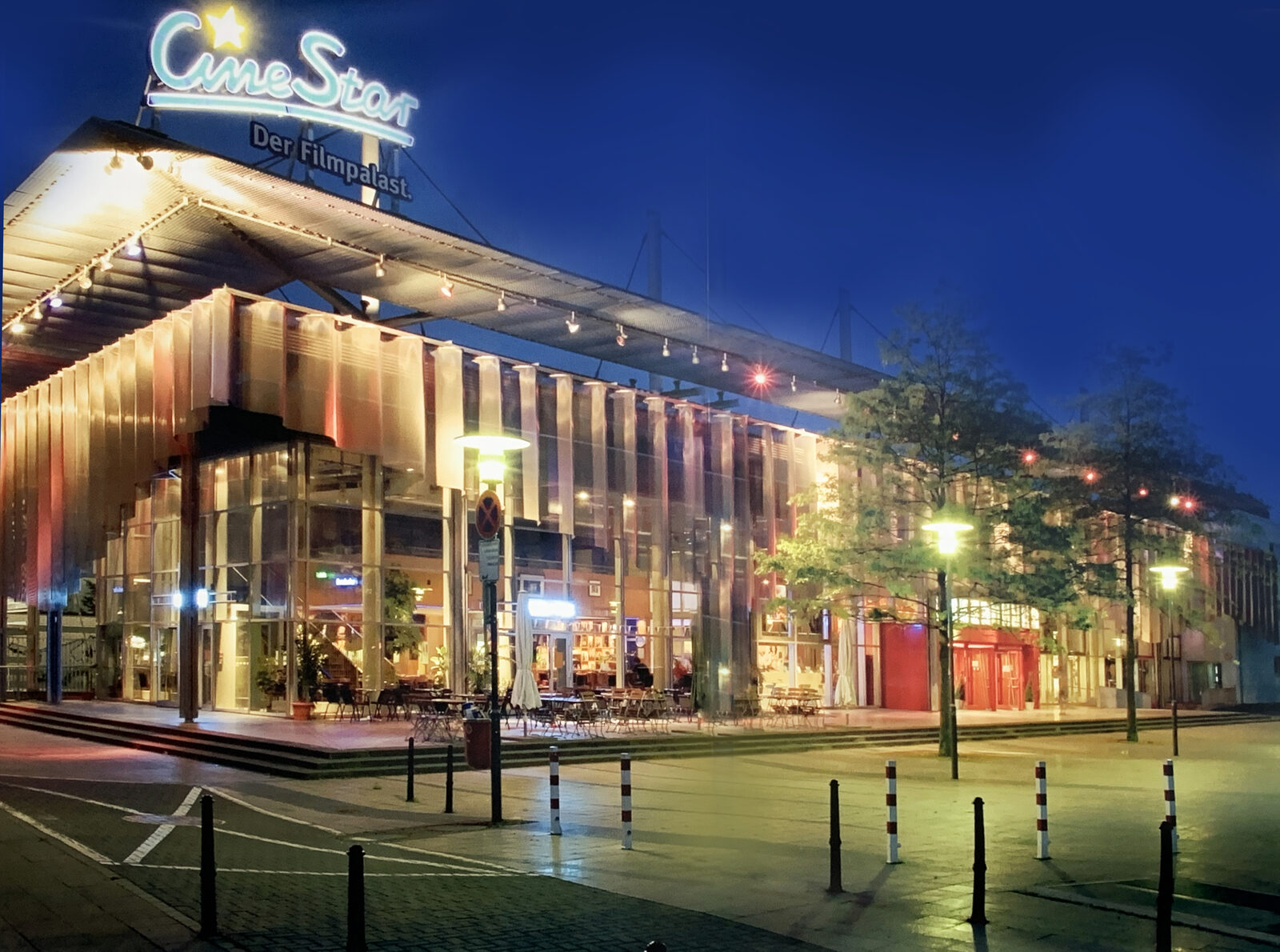 Der beleuchtete Glasbau des CineStar Filmpalastes an der Hansaallee bei Nacht