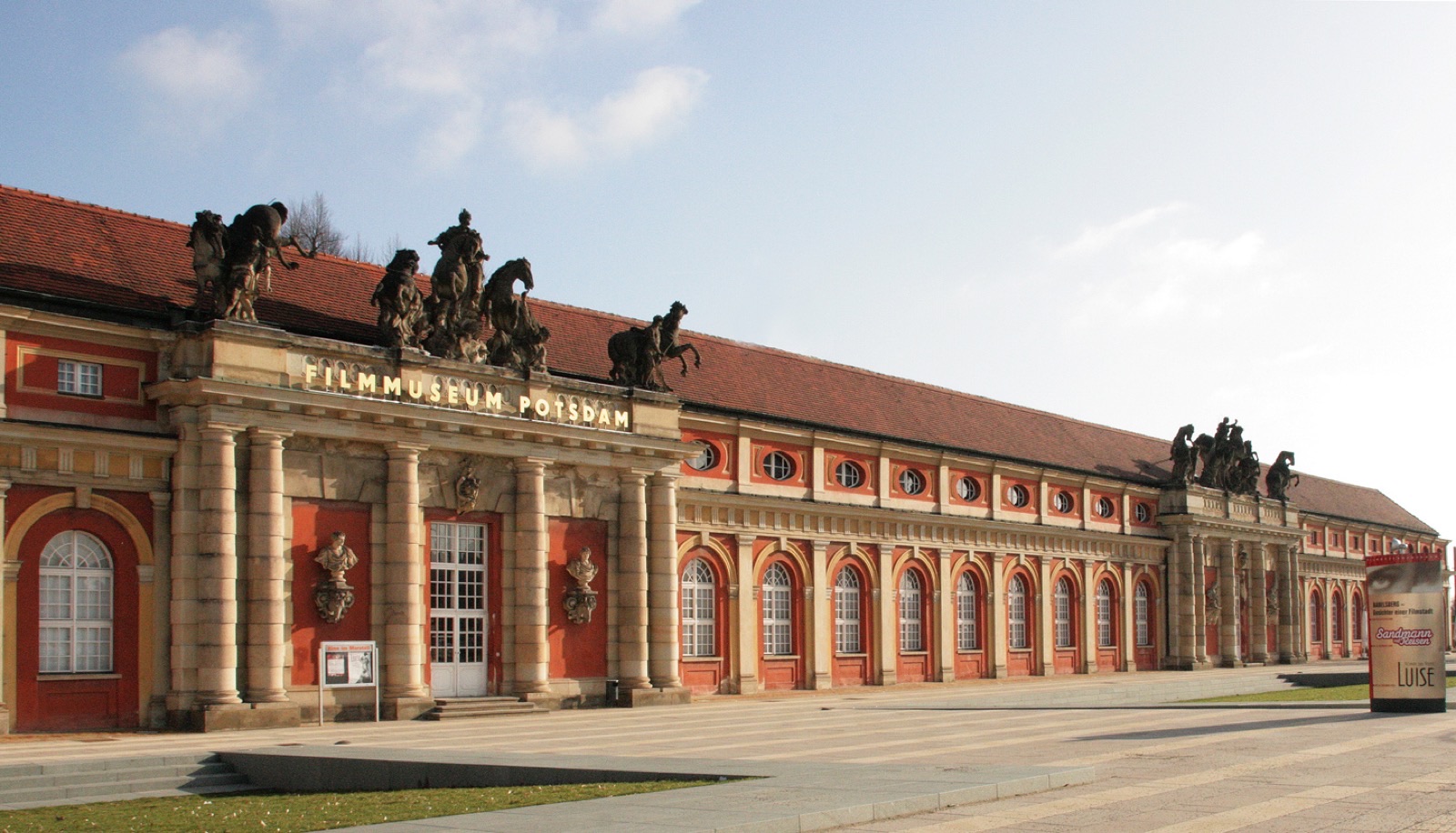 Langgestreckter barocker Marstall mit Pferdeskulpturen auf dem Dach und dem Schriftzug Filmmuseum Potsdam