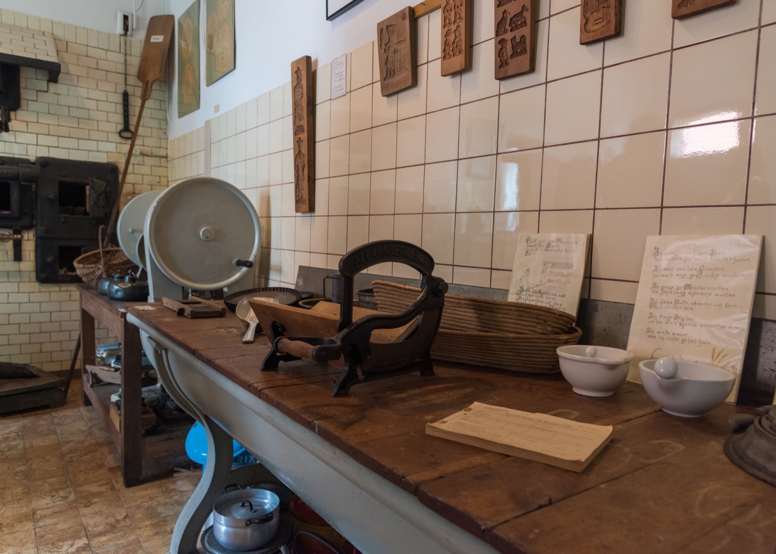 Historische Backstube mit Knetmaschine, Brötchenportionierer und Holzbackschaufel vor weißen Fliesen