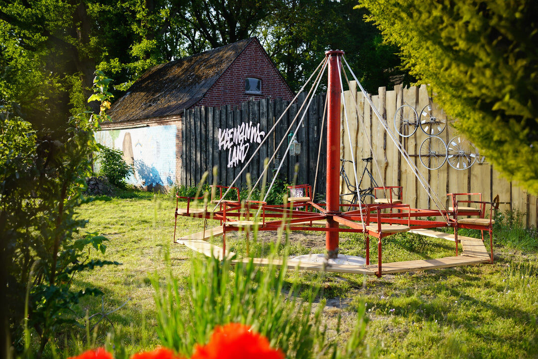 Ein rotes Karussell auf der Wiese im Kliemannsland, dahinter eine Scheune mit dem Kliemannsland-Schriftzug
