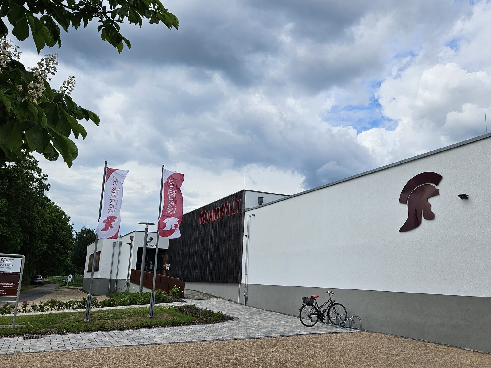 Außenansicht der RömerWelt mit Fahnen und dem Römerhelm an der Fassade