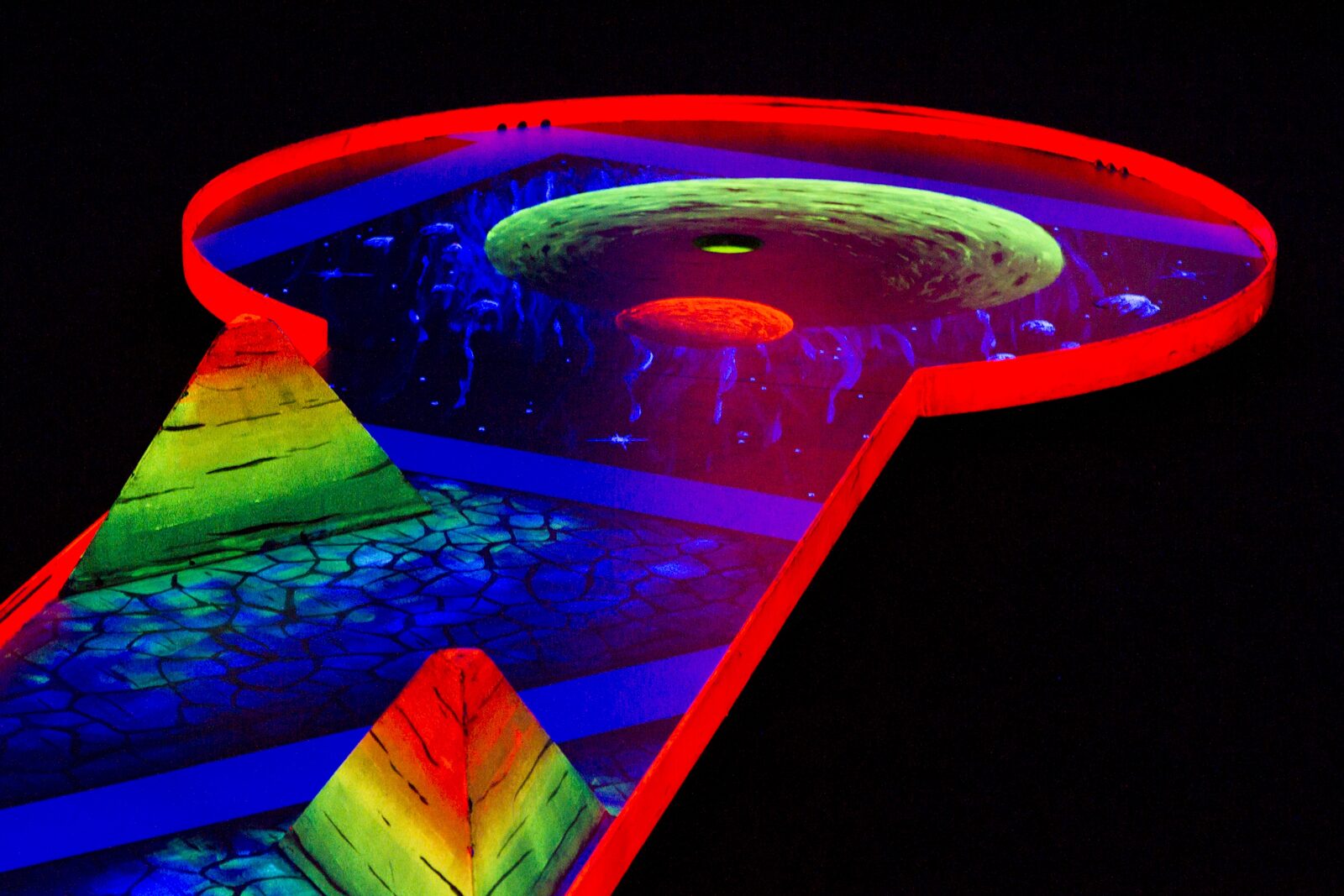 Schwarzlicht-Minigolfbahn im Weltraumthema mit leuchtendem Planeten