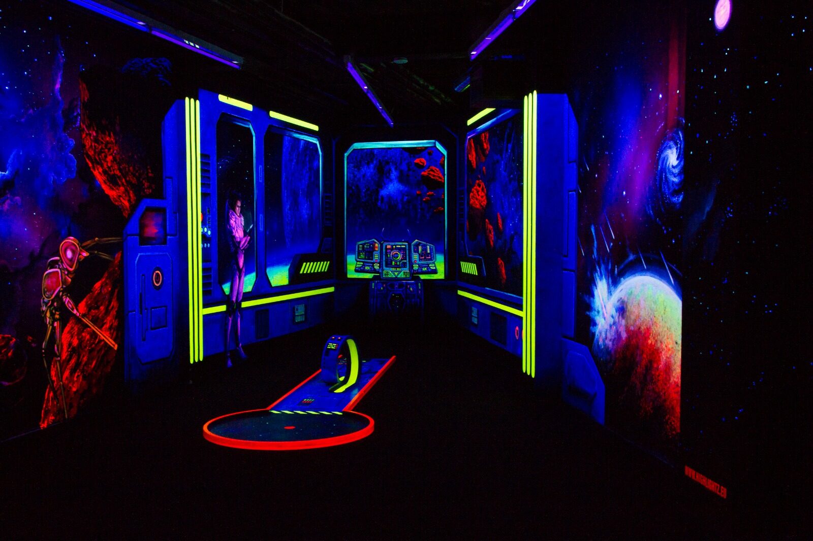 Minigolfbahn im Raumschiff-Themenraum unter Schwarzlicht
