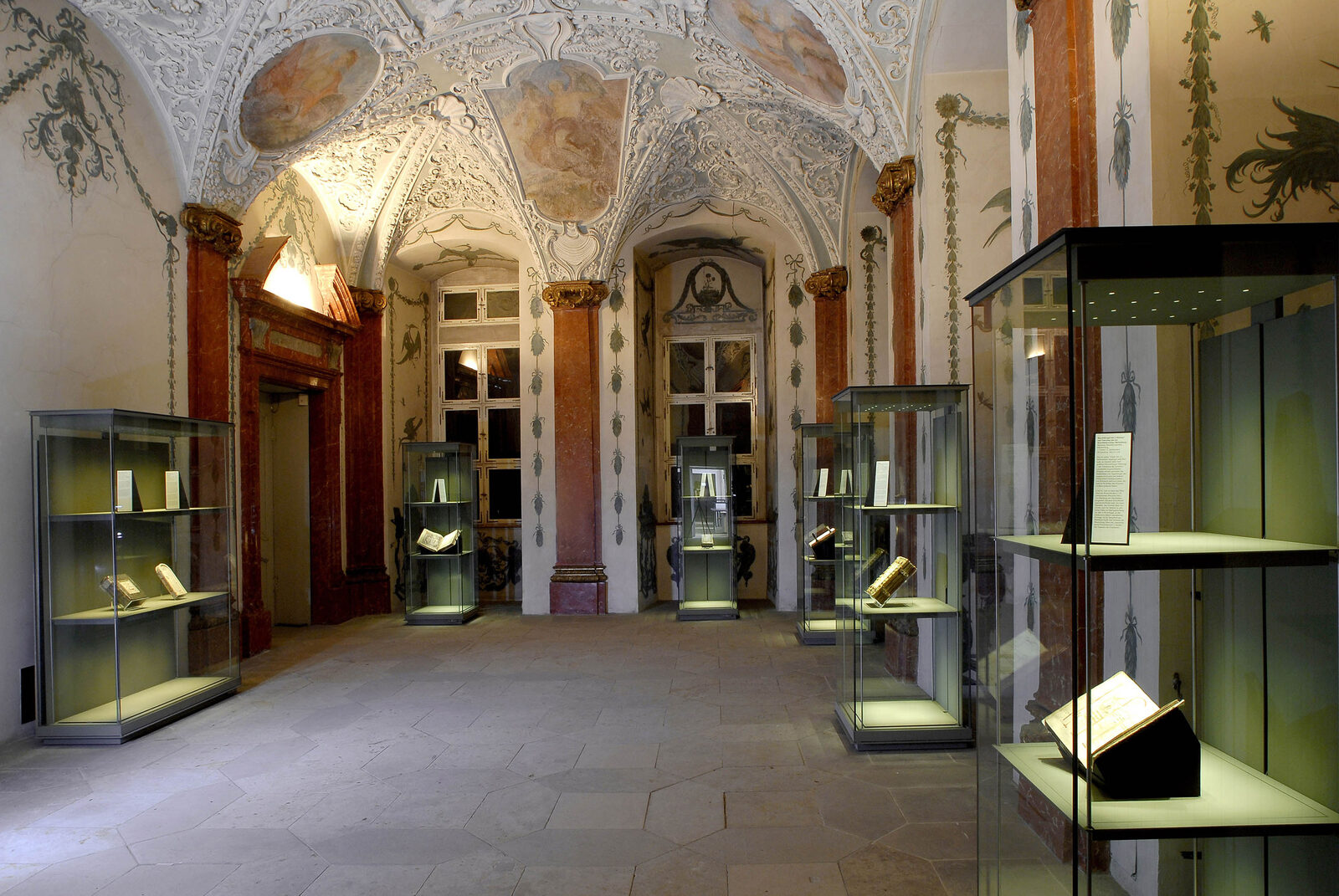 Ausstellungsraum der Staatsbibliothek Bamberg mit Vitrinen unter barockem Stuckgewölbe