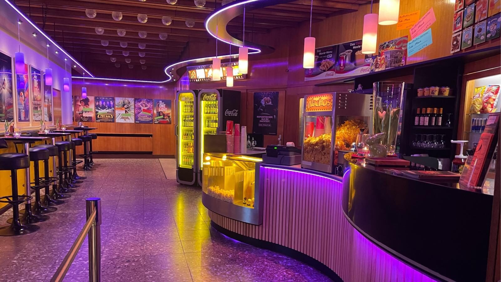 Das farbig beleuchtete Foyer des Weltspiegel Finsterwalde mit geschwungenem Tresen und Filmplakaten